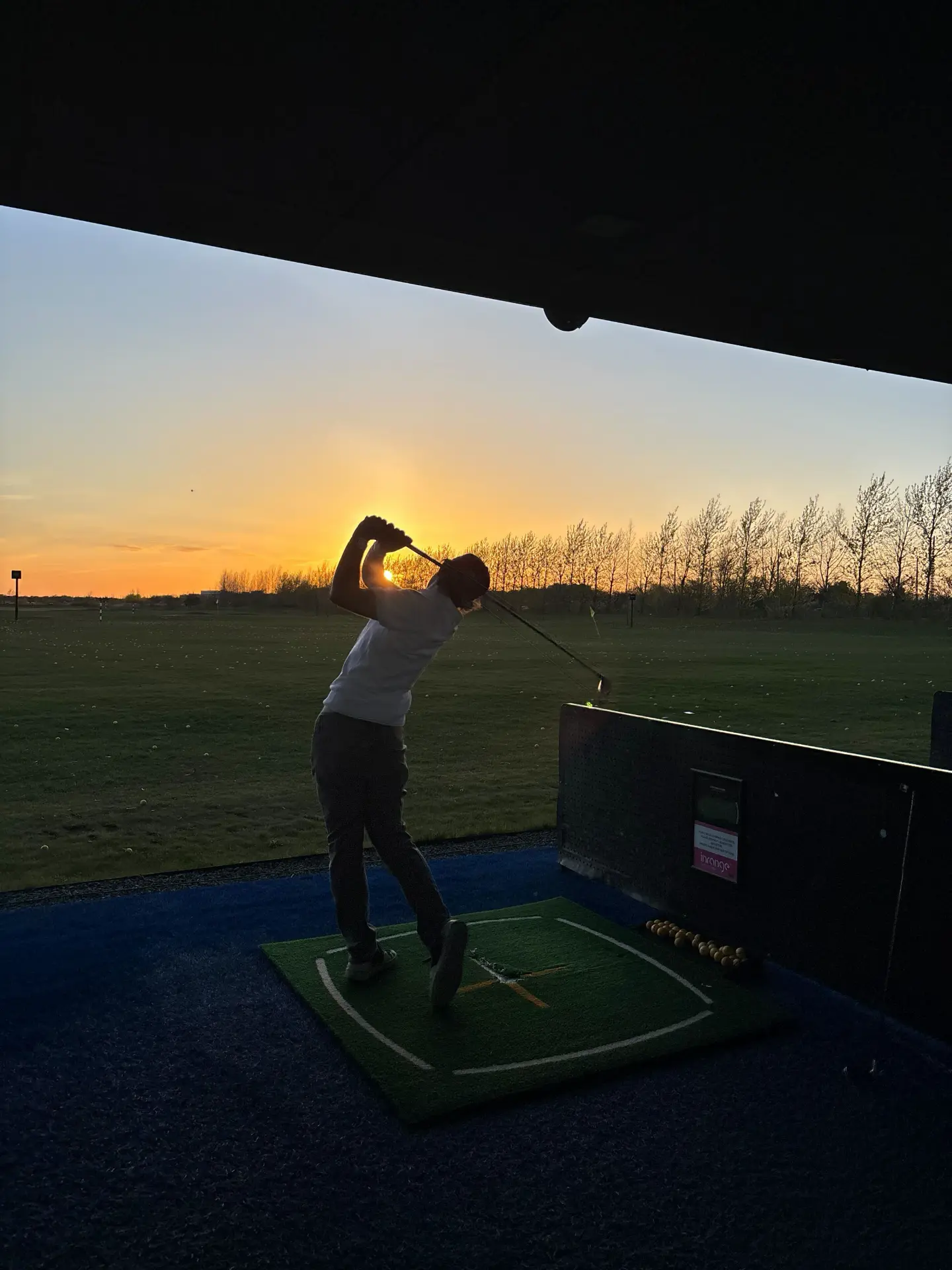 Golfer at driving range at sunset