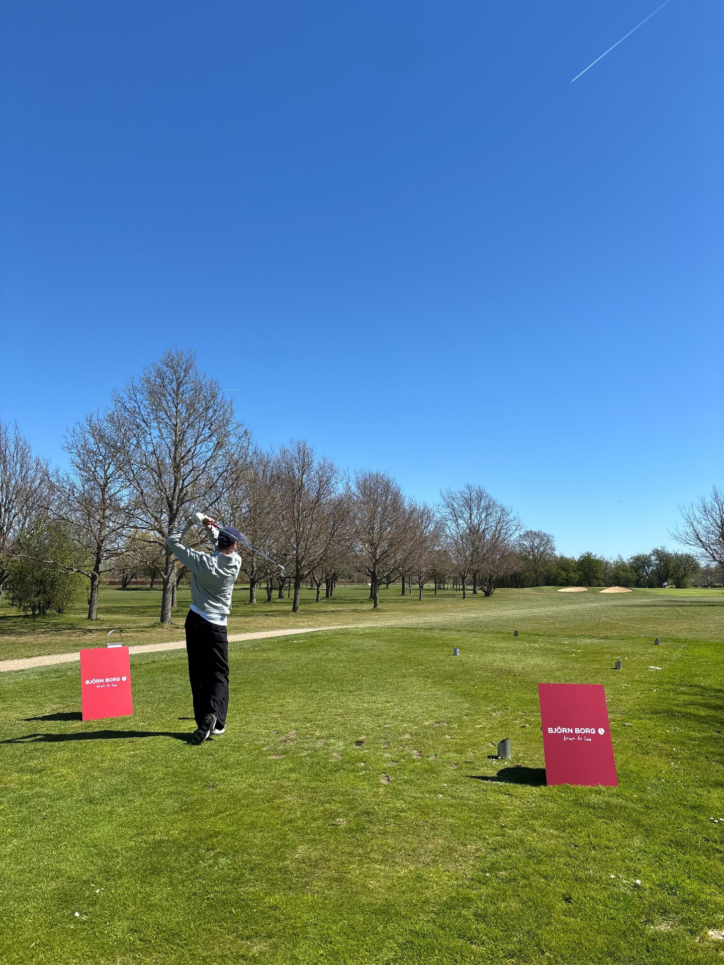 Player teeing off on a sunny day
